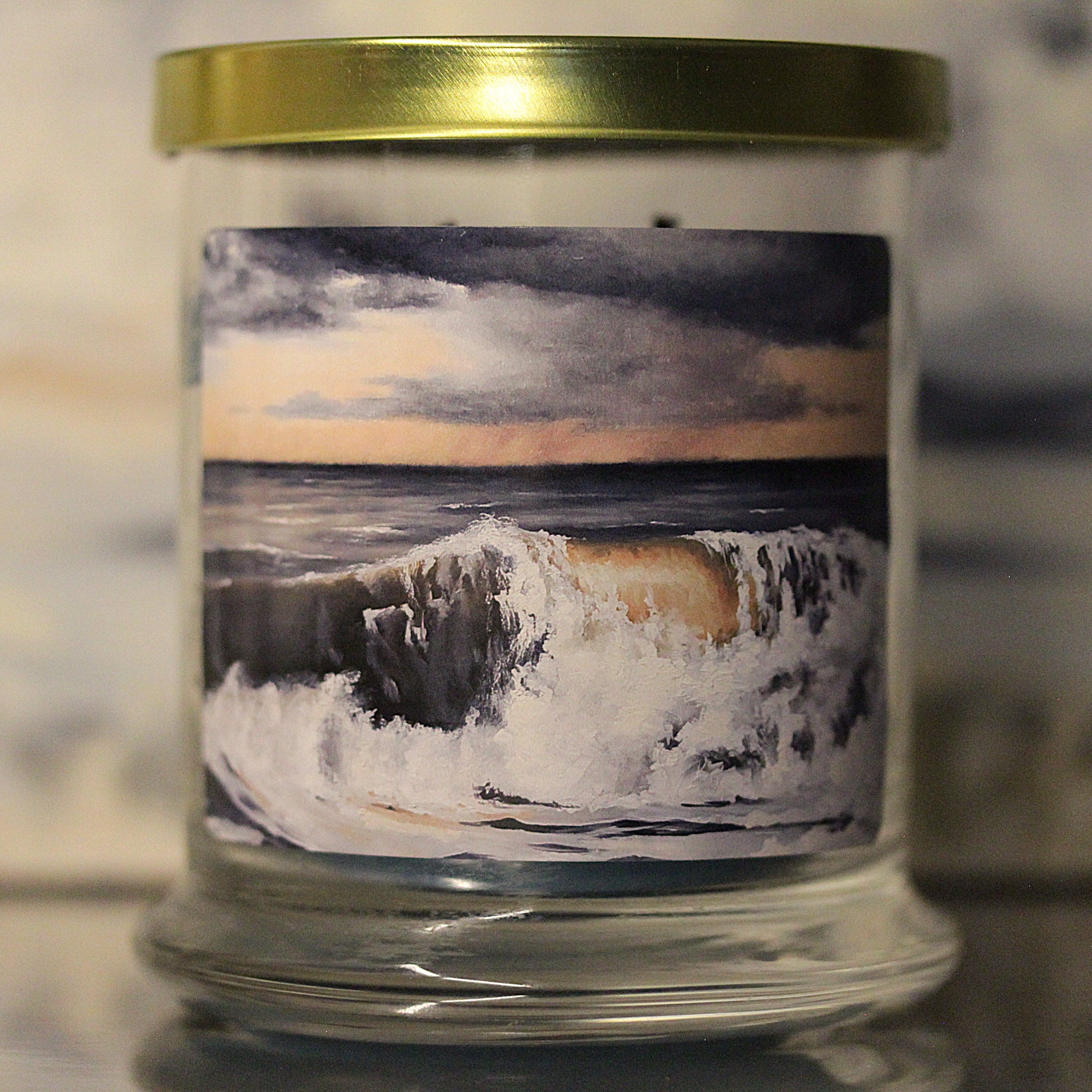 Close up of an unlit sea salt scented candle with coastal artwork on the glass jar.