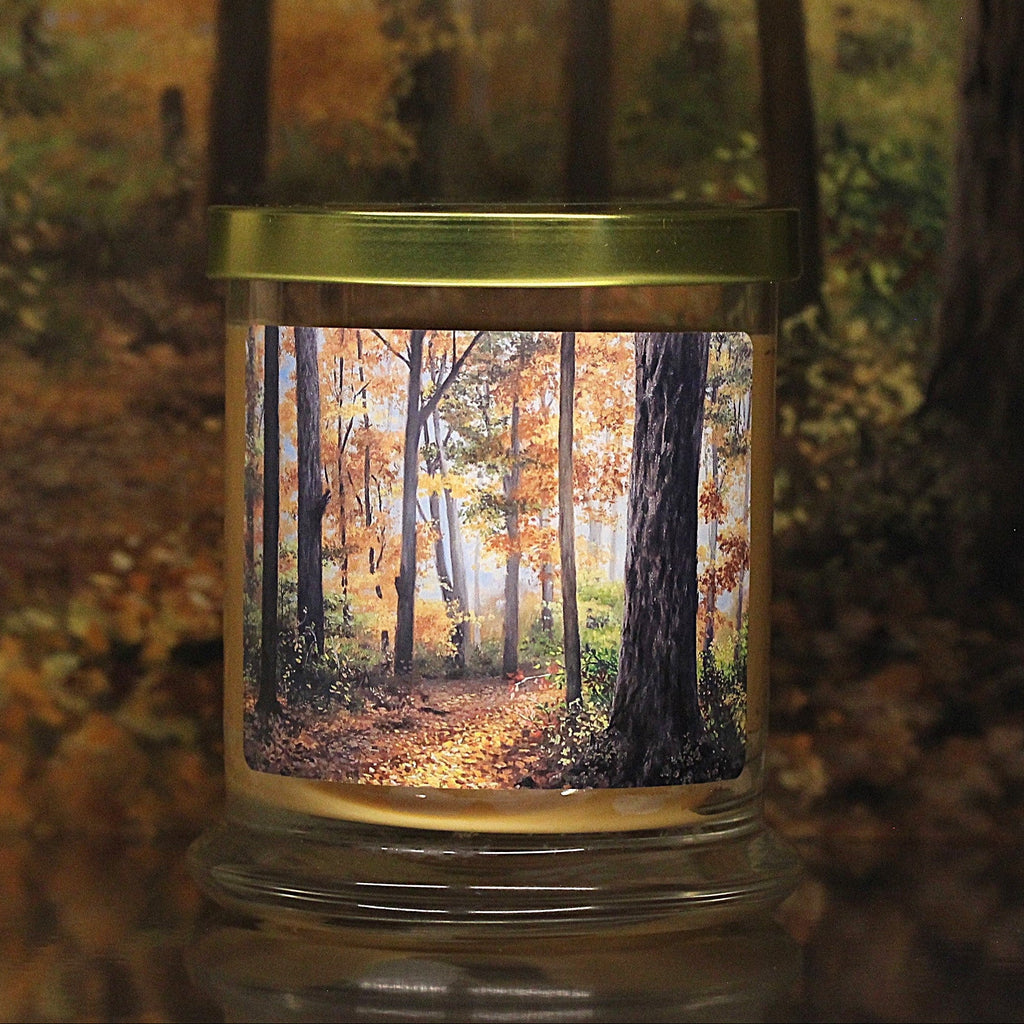 Close up view of a leaves scented candle with original decorative artwork on the glass jar.