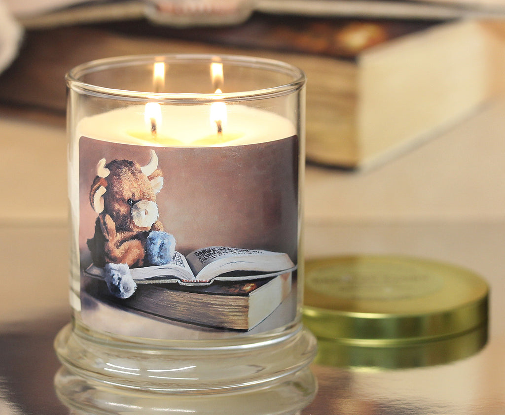 Close up view of a lit cashmere scented candle with original cozy artwork on the glass jar.