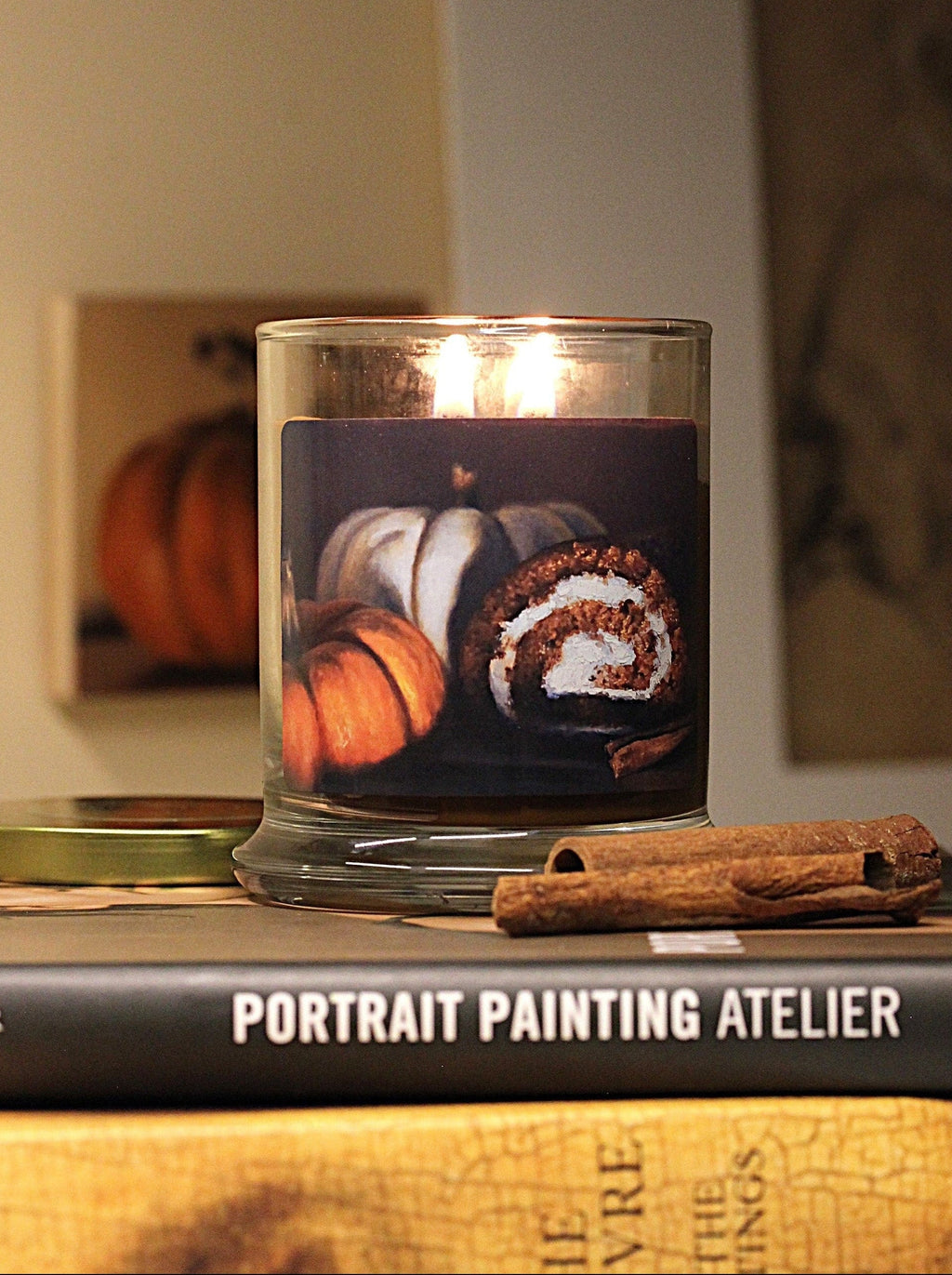 Double wicked, pumpkin scented, 9 oz. candle with original decorative artwork on the glass jar in an aesthetic environment.