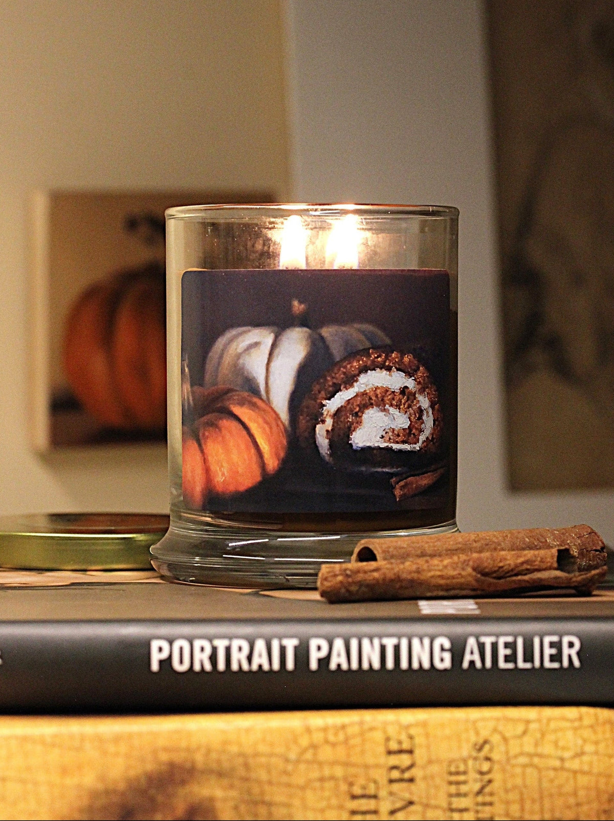 Double wicked, pumpkin scented, 9 oz. candle with original decorative artwork on the glass jar in an aesthetic environment.