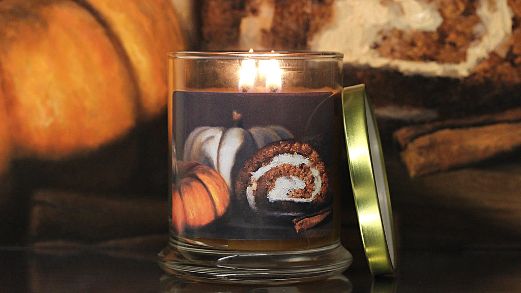 Close up view of a lit, pumpkin scented candle with original decorative artwork on the glass jar.